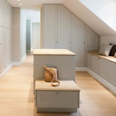 an empty room with white cupboards and wooden flooring, along with a bench in the foreground