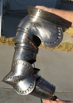 a close up of a person's hand holding a metal object in the shape of a helmet