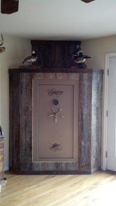 two birds sitting on top of a wooden cabinet in a room with hard wood floors