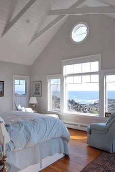 a bed sitting in a bedroom next to two windows and a chair on top of a hard wood floor