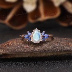 an oval shaped ring with blue sapphire stones on top and two pear shaped diamonds in the middle