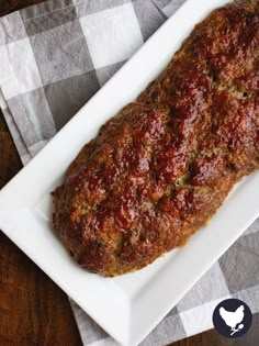 a meatloaf on a white plate sitting on a checkered table cloth