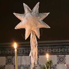 a white star hanging from the ceiling next to two candles