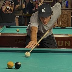 a man leaning over to hit a pool ball