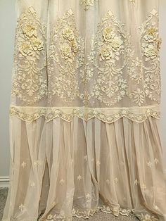 a curtain with flowers on it hanging in front of a white wall and carpeted floor