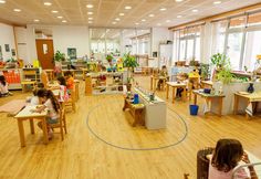 children sitting at desks in a classroom with wooden floors