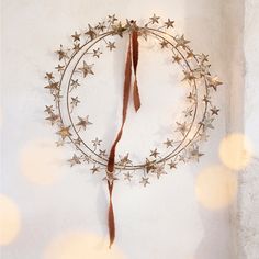 a metal wreath with stars hanging from it's side on a wall next to some lights