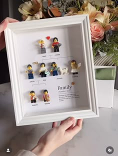 a person holding up a frame with legos on it and flowers in the background