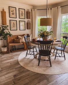 a dining room table and chairs in front of a window with pictures on the wall