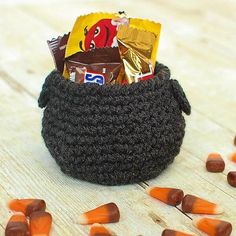 a crocheted basket filled with candy and candies on top of a wooden table