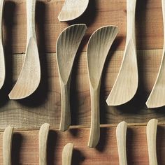 several wooden spoons lined up against a wall with different shapes and sizes on them