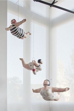 three ceramic figures hanging from strings in front of a window