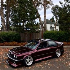 a maroon car parked in front of some trees