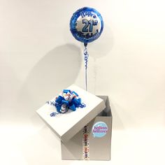 a blue 21st birthday balloon sitting on top of a white box