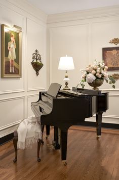 a grand piano in a living room next to a lamp and painting on the wall