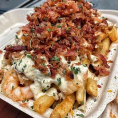 a white plate topped with french fries covered in cheese and bacon next to other food items