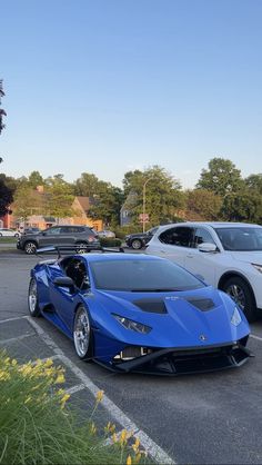 two blue cars parked in a parking lot next to each other on a sunny day