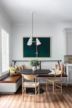 a dining room table with chairs and a bench in front of a chalkboard on the wall