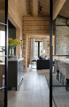 an open living room and dining area with wood paneling on the walls, wooden floors and ceiling