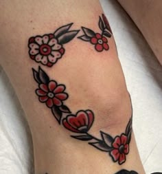 a woman's foot with red flowers and leaves on the bottom of her leg