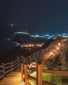 the stairs lead down to the beach at night with bright lights on them and in the distance, there is an ocean view