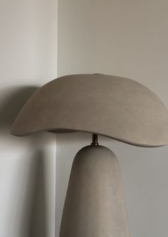 a lamp that is on top of a table next to a wall with a plant in it