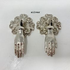 two silver metal gloves with flowers on them and the words silver written in white letters