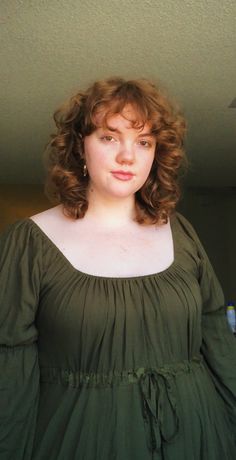 a woman with curly hair wearing a green dress