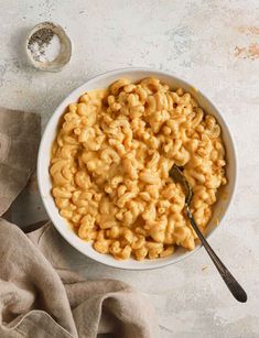 a white bowl filled with macaroni and cheese on top of a beige napkin