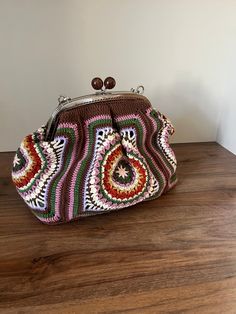 a crocheted purse sitting on top of a wooden table next to a wall