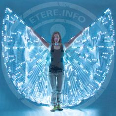 a woman standing in front of a large butterfly shaped light up display with her arms outstretched