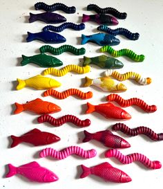 many different colored plastic fish on a white surface