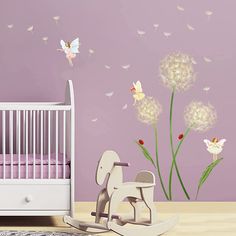 a baby's room with a crib, rocking horse and dandelion wall decals