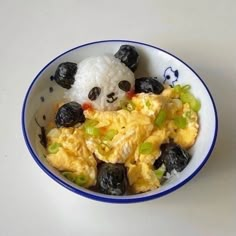 a bowl filled with rice and black olives next to a small stuffed panda bear