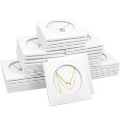 a stack of white cards with gold necklaces on top of each card in front of a white background