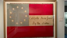 an old american flag is hanging on the wall in a museum display case with other artifacts