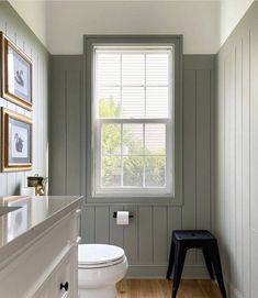 a white toilet sitting next to a window in a bathroom on top of a hard wood floor