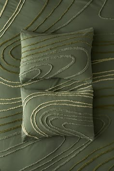 two green pillows with gold thread on them