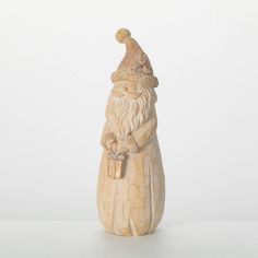 a small wooden santa clause figurine with a present in his hand on a white surface