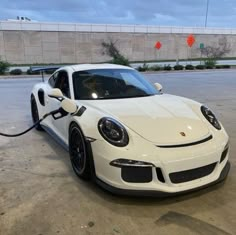 a white sports car with an electric charger hooked up to it