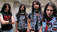 three men with long hair standing in front of a wall