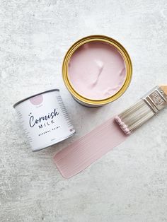 a can of paint next to a pink brush