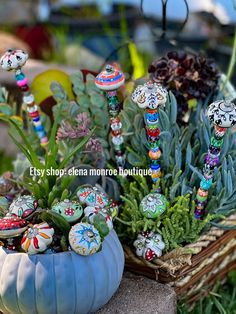 an assortment of fake flowers and plants in a blue pumpkin shaped planter on the ground