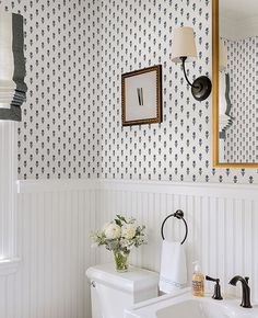 a white toilet sitting next to a sink in a bathroom under a wall mounted mirror