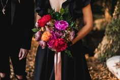 a woman in a black dress holding a bouquet of flowers