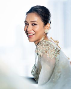 a woman in a white dress smiling and looking at the camera with an open smile on her face