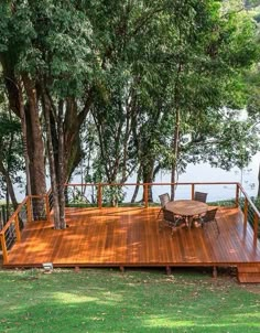 a wooden deck with table and chairs next to trees