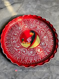 a red and gold plate sitting on top of a marble floor next to a wall