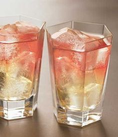 two glasses filled with ice sitting on top of a table