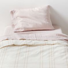 an unmade bed with pink sheets and pillows